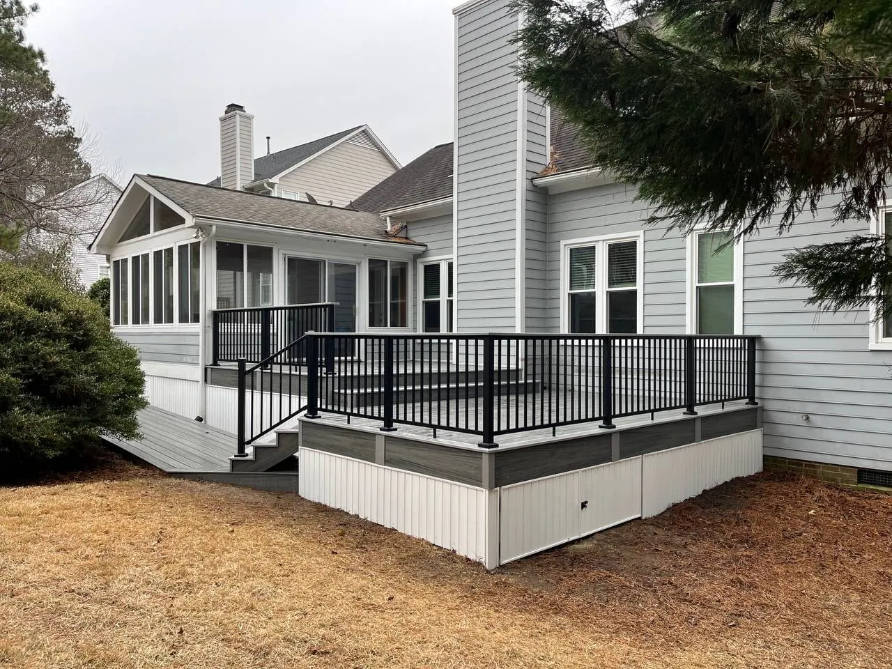 Composite deck with black aluminium railing and white skirting beside a screened porch