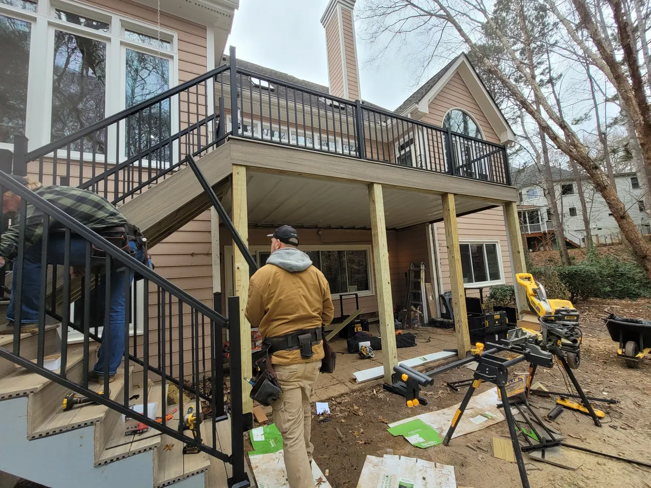 Mission Decks crew building an elevated deck with black railing above a walk-out basement