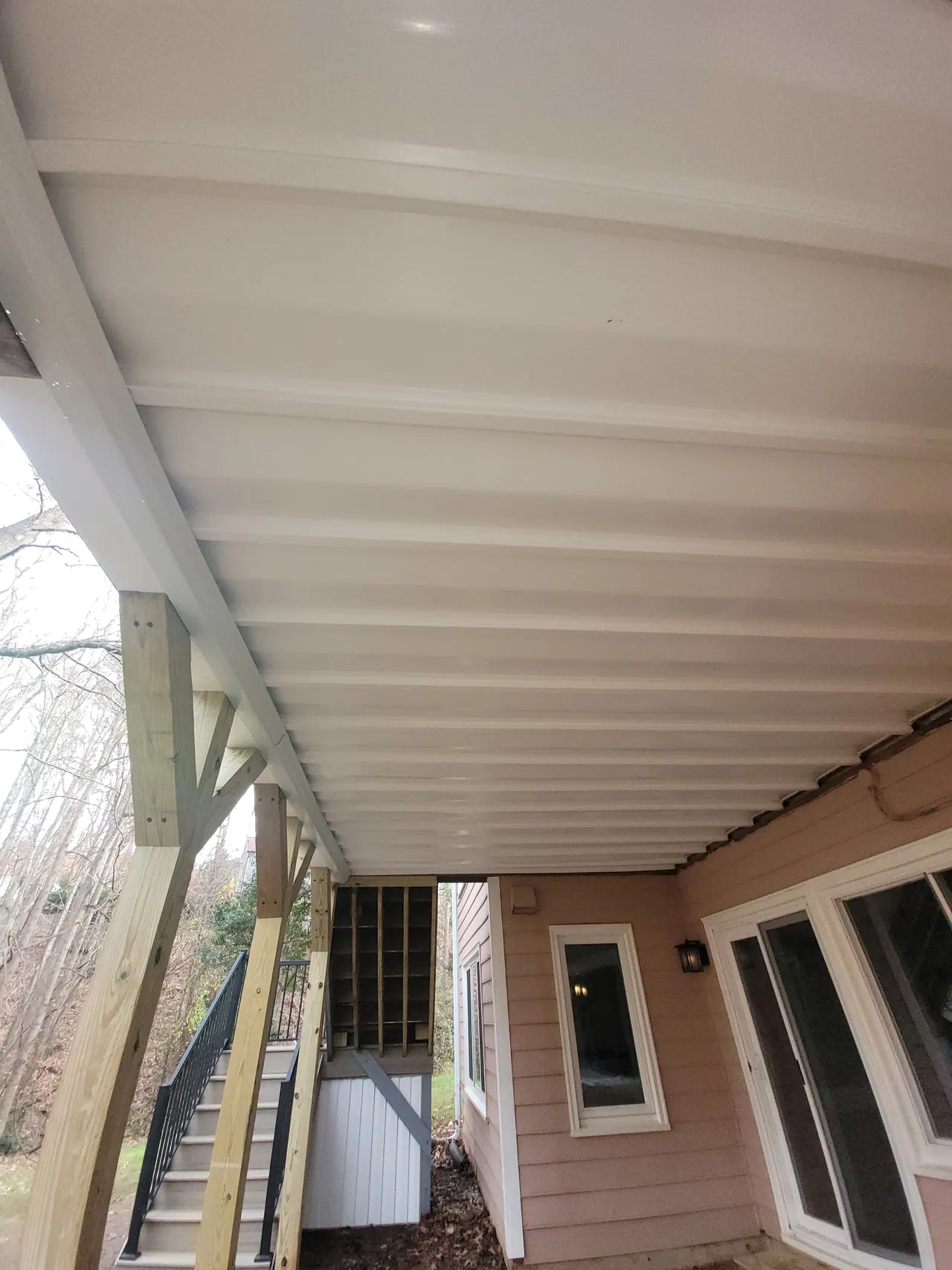 Finished under-deck ceiling running between timber beams beneath an elevated deck