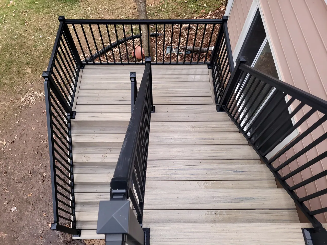 Overhead view of deck stairs turning through black aluminum railing
