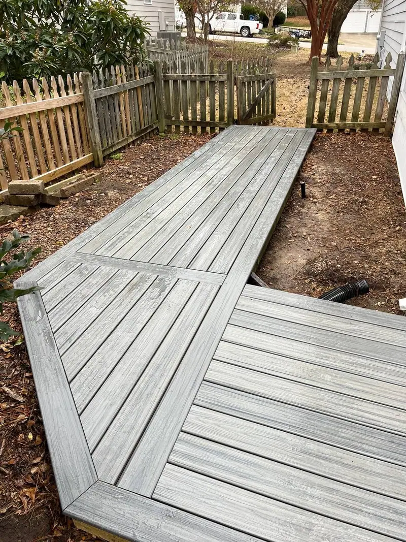 Weathered grey composite walkway running alongside a wooden fence