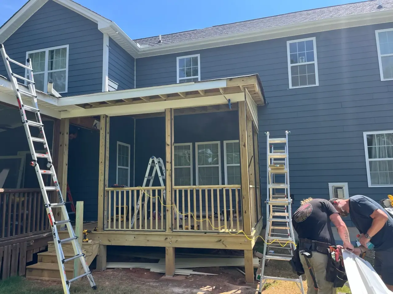 Screened porch under construction with ladders and framing in place
