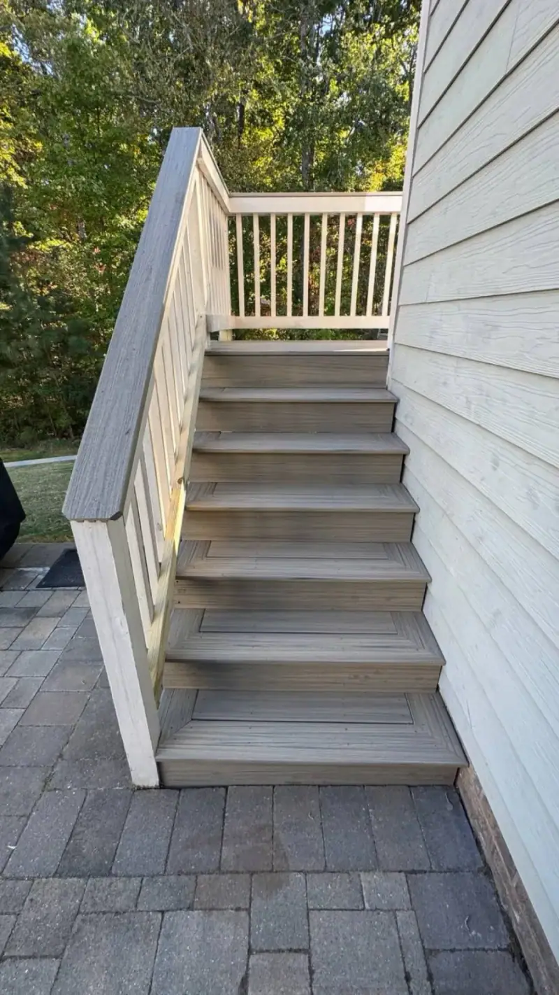 Deck stairs with white railing descending to a paver patio