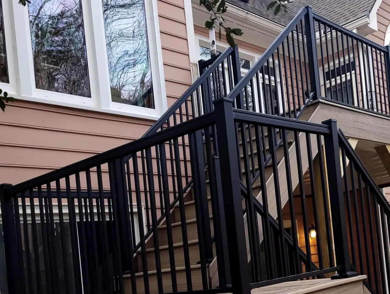 Black aluminum railing and stairs lit warmly at dusk