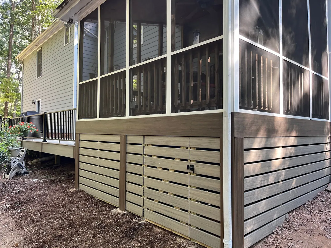 Screened porch with dark screen frames above horizontal composite skirting on a cream-sided home
